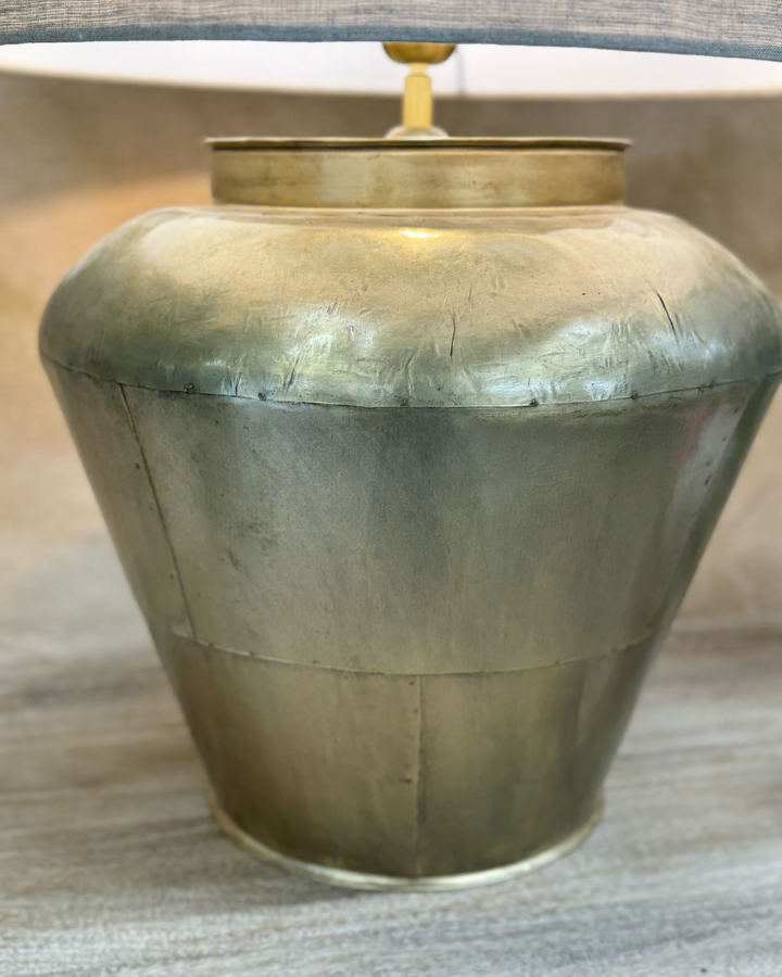 Lámpara de mesa de latón con pantalla de lino y base ancha y curva.