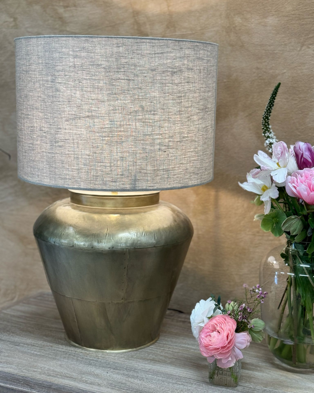 Lámpara de mesa de latón con pantalla de lino y base ancha y curva.