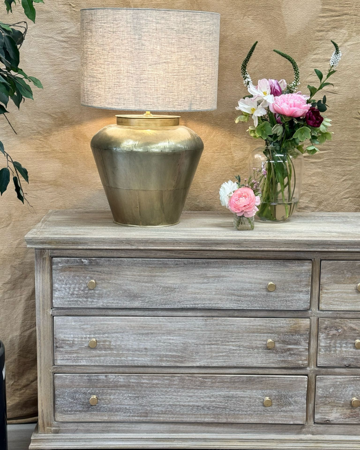 Lámpara de mesa de latón con pantalla de lino y base ancha y curva.