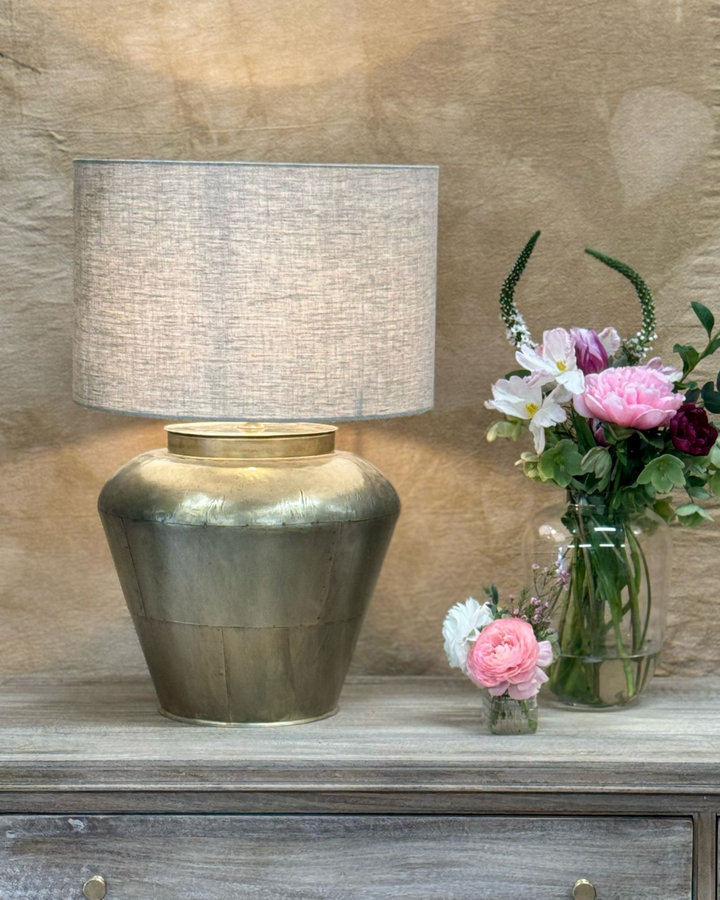 Lámpara de mesa de latón con pantalla de lino y base ancha y curva.