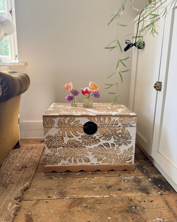 Baúl de madera de mango tallado a mano con diseño de hojas de monstera y acabado blanqueado.