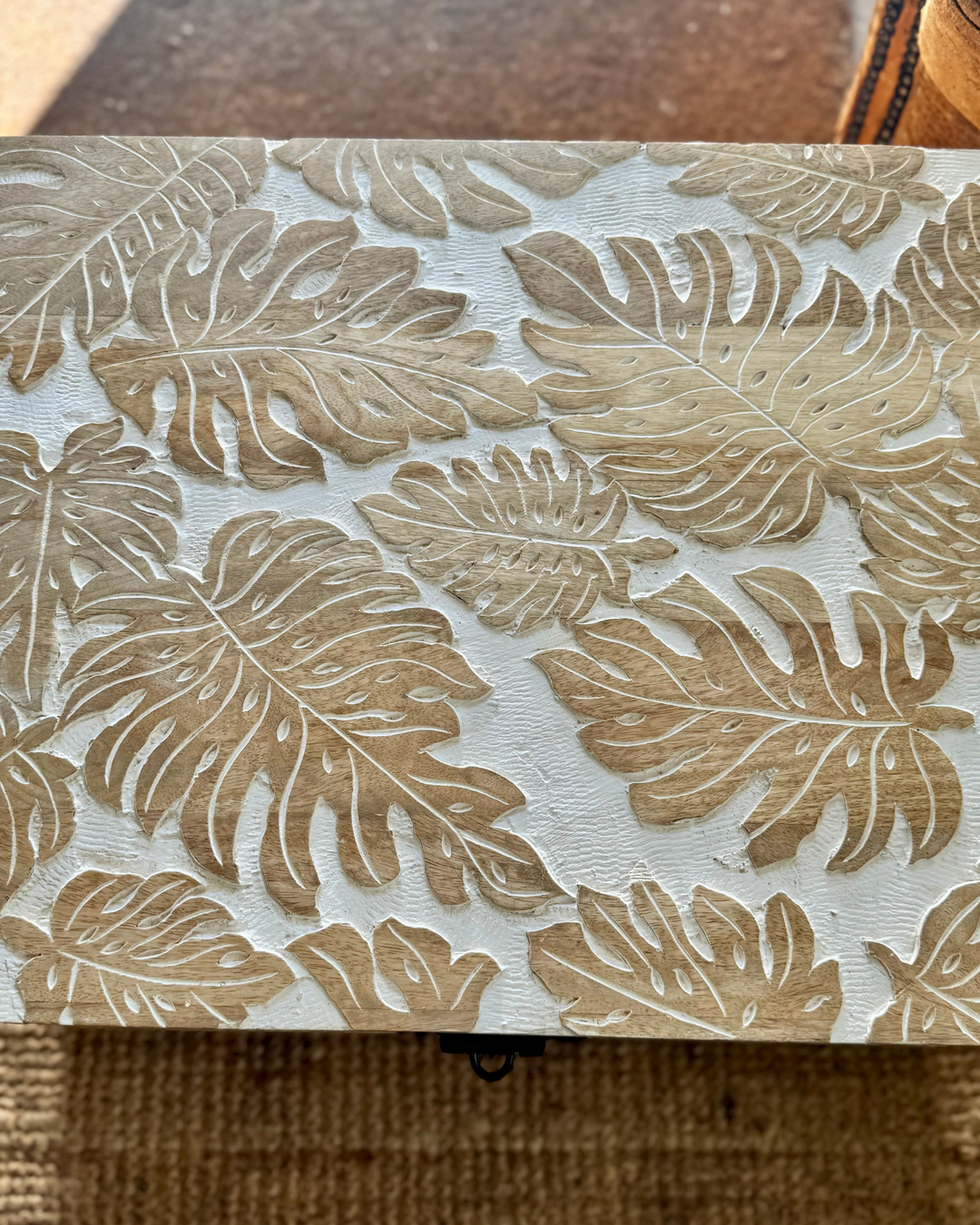 Baúl de madera de mango tallado a mano con diseño de hojas de monstera y acabado blanqueado.
