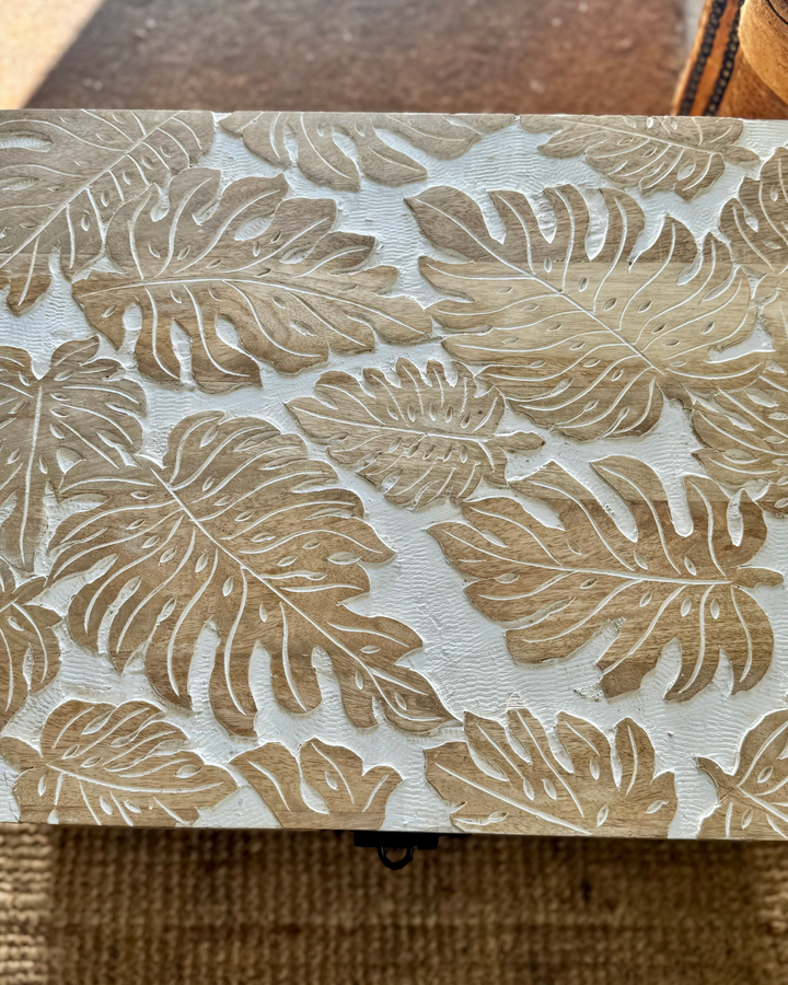 Baúl de madera de mango tallado a mano con diseño de hojas de monstera y acabado blanqueado.