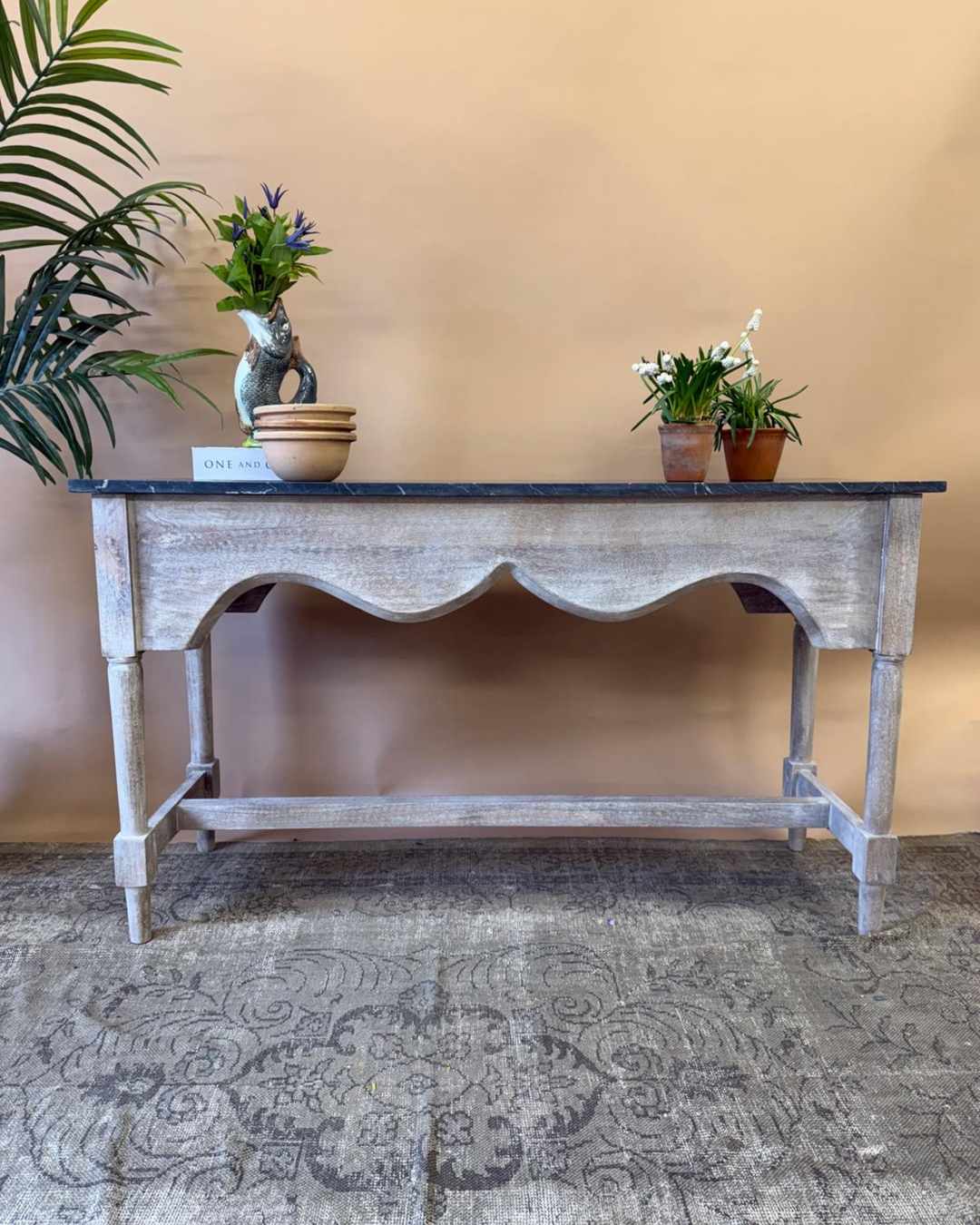 Wooden console table with decorative items against a beige wall