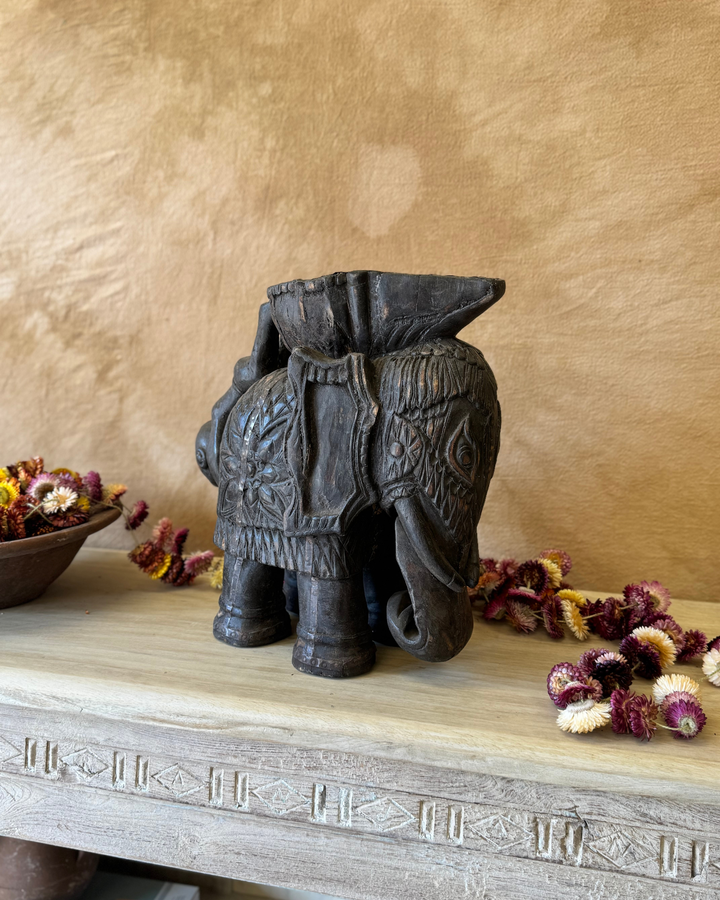 Maceta vintage con forma de elefante tallada a mano, acabado oscuro y asa con figura invertida. 