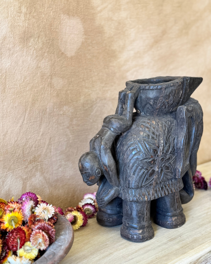 Maceta vintage con forma de elefante tallada a mano, acabado oscuro y asa con figura invertida. 
