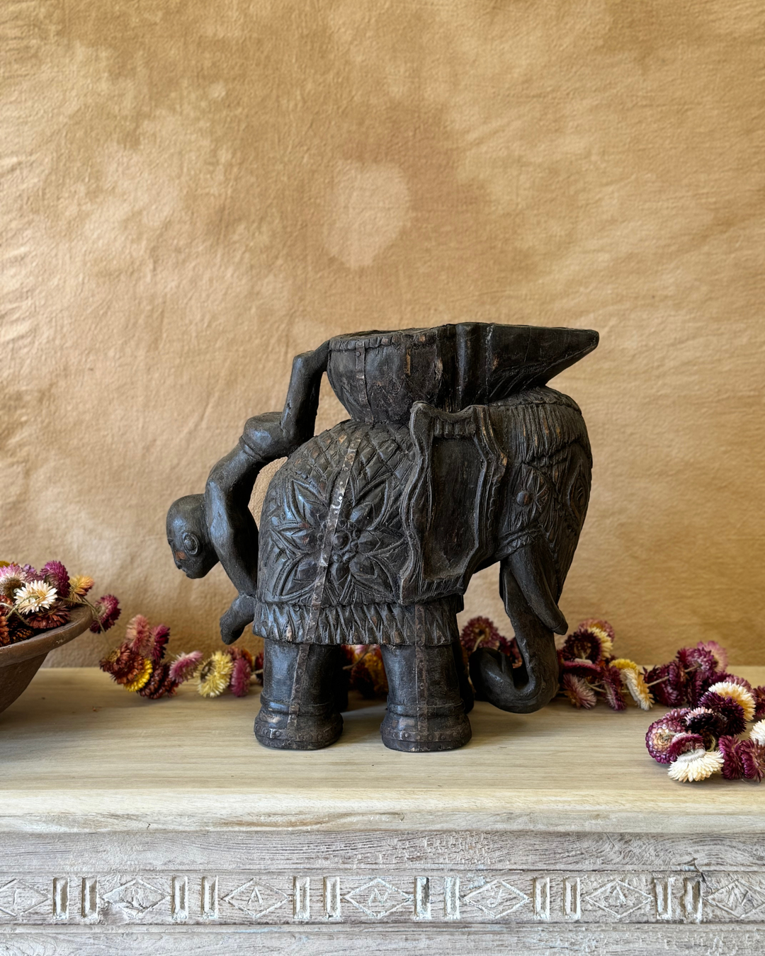 Maceta vintage con forma de elefante tallada a mano, acabado oscuro y asa con figura invertida. 