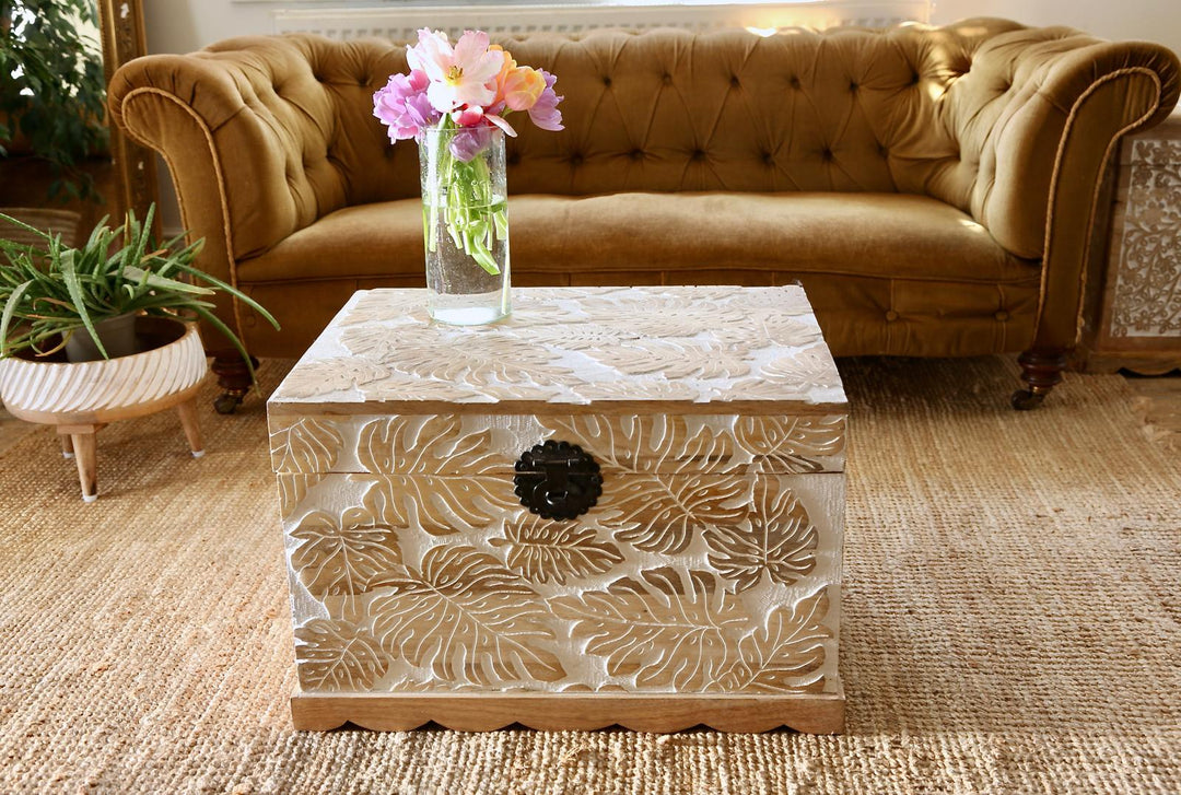 Baúl de madera de mango tallado a mano con diseño de hojas de monstera y acabado blanqueado.
