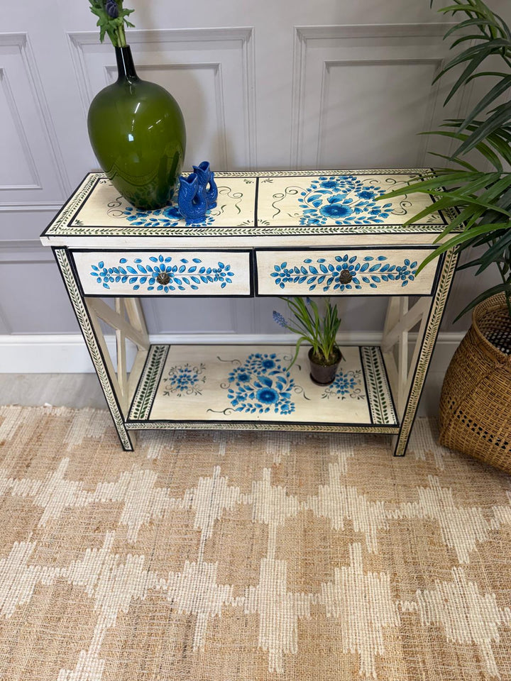 Consola pintada a mano, acabado crema con detalles florales en turquesa y dos cajones.