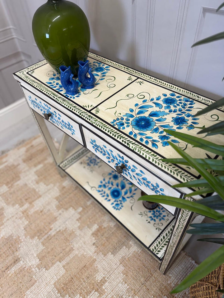 Consola pintada a mano, acabado crema con detalles florales en turquesa y dos cajones.